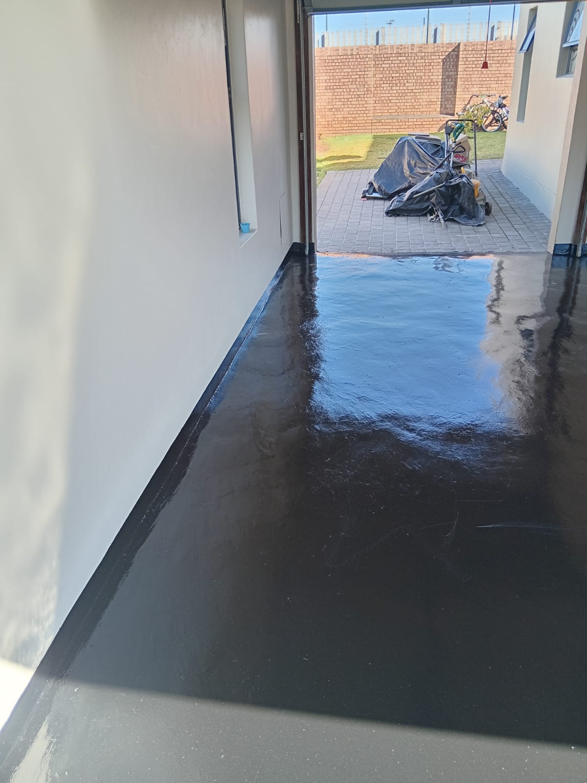 Freshly sealed black garage floor with clean edge lines